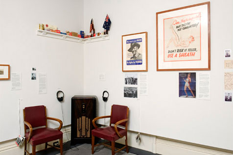 Gallery’s north-east corner, with two red chairs flanking an old floor radio; a shelf is mounted above, various ephemera hangs to the right