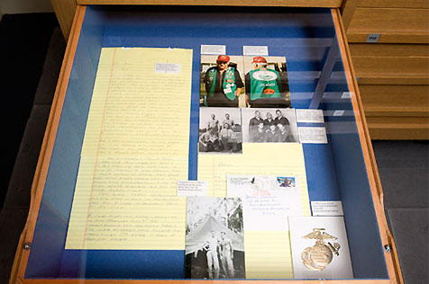 Open drawer in a wooden display case, holding two colour photos and three black-and-white photos, plus a card and a long, handwritten letter
