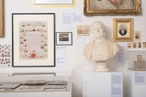 Close up of a white bust, small portrait pictures alongside other ephemera