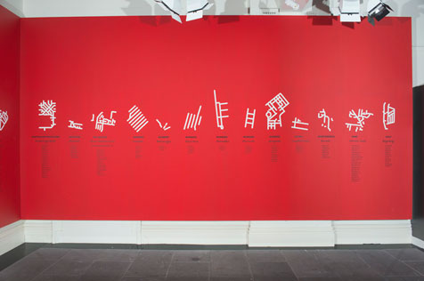 Exhibition installation of stylised white maps on red wall