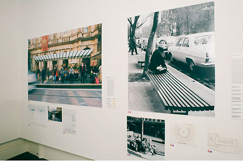 Gallery’s east wall, with large colour photo of tram shelter and black-and-white photo of young woman on street seating; two small photos hang below