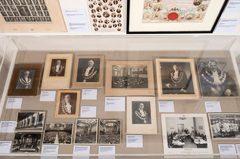 Black and white photographs of men in full mayoral regalia in a glass cabinet