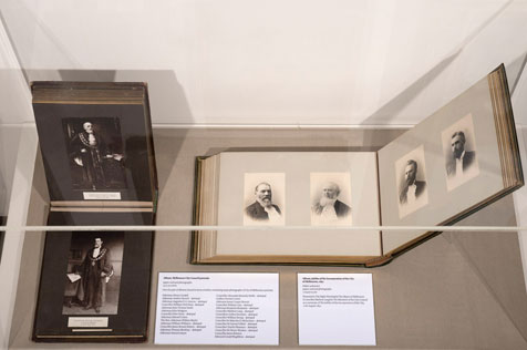 Photo album in a display cabinet featuring four sepia headshots