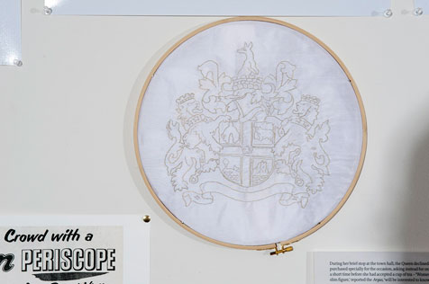 Embroidery hoop with coat of arms sewn in gold thread onto a white fabric