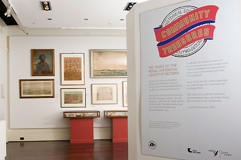 Entrance to Community Treasures, with the exhibition intro panel to the right and display cases and artworks visible on the left