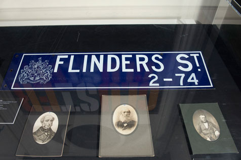 Blue Flinders Street sign and three sepia photographs
