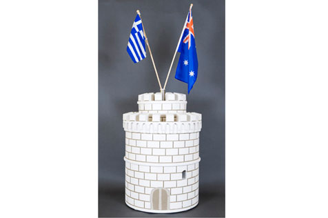 Model of a white round tower topped with Greek and Australian flags