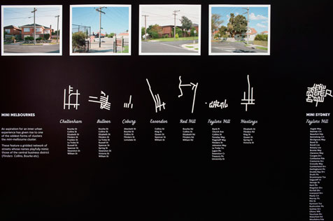 Four photos of suburban street intersections on a black wall with stylised white maps and writing