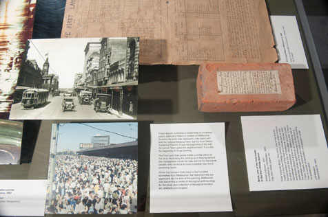 Close up of photographs, a brick and other exhibits under a glass case