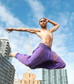 Dancer leaping in the air, city buildings in the background
