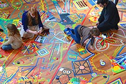 Children sitting on floor decorated with coloured tape