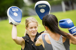 Woman and personal trainer boxing in a park