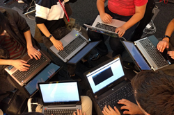 People sitting a circle, using laptops.