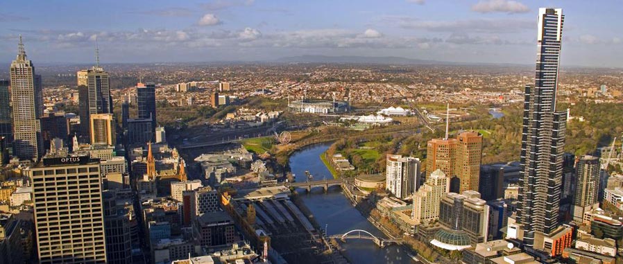 Elevated view of Melbourne city buildings and Yarra River, suburban outskirts in the background