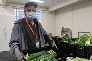 Community Champion Cory Memery, holding a crate of vegetables