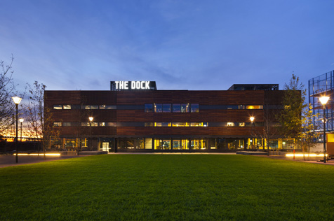 A lawn in front of a three-storey building with a sign saying The Dock on the top floor.