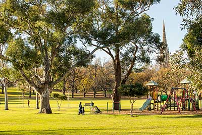 A playground next to large trees in Fawkner Park