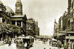 Historical image of Melbourne city street, showing town hall and surrounding buildings, vehicles and pedestrians
