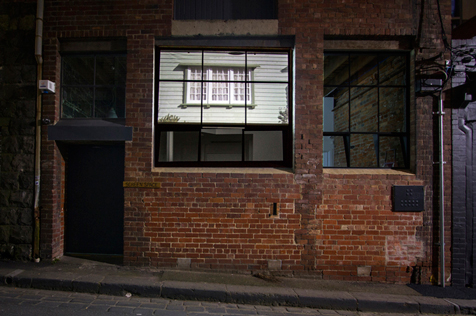 Red brick building facade with image of a window set in weather boards projected on its window