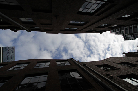 Looking up at blue sky and clouds framed by buildings