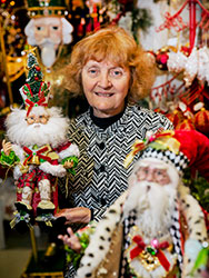 Connie Martino surrounded by Christmas ornaments and holding a Santa figurine.