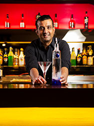 Damion de Silva behind the bar serving a cocktail at Khokolat Bar.