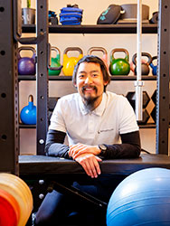 Yujin Lim surrounded by exercise equipment including balls and kettle bells.