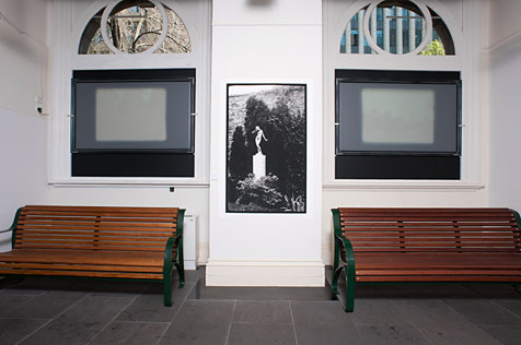 Large black and white image on wall with wooden benches on either side