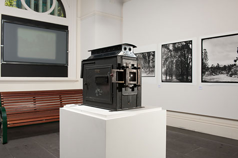 Solid metal projector with screen and large black and white photograph prints on a white wall