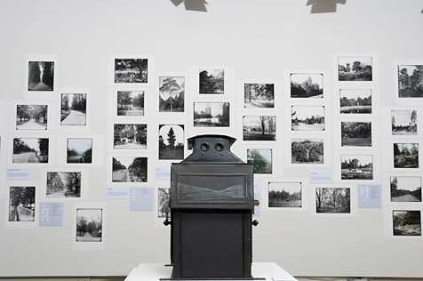 Solid metal projector and black and white photograph prints on a white wall