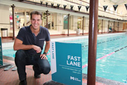 Matt Welsh crouches beside a swimming pool, smiling at the camera.