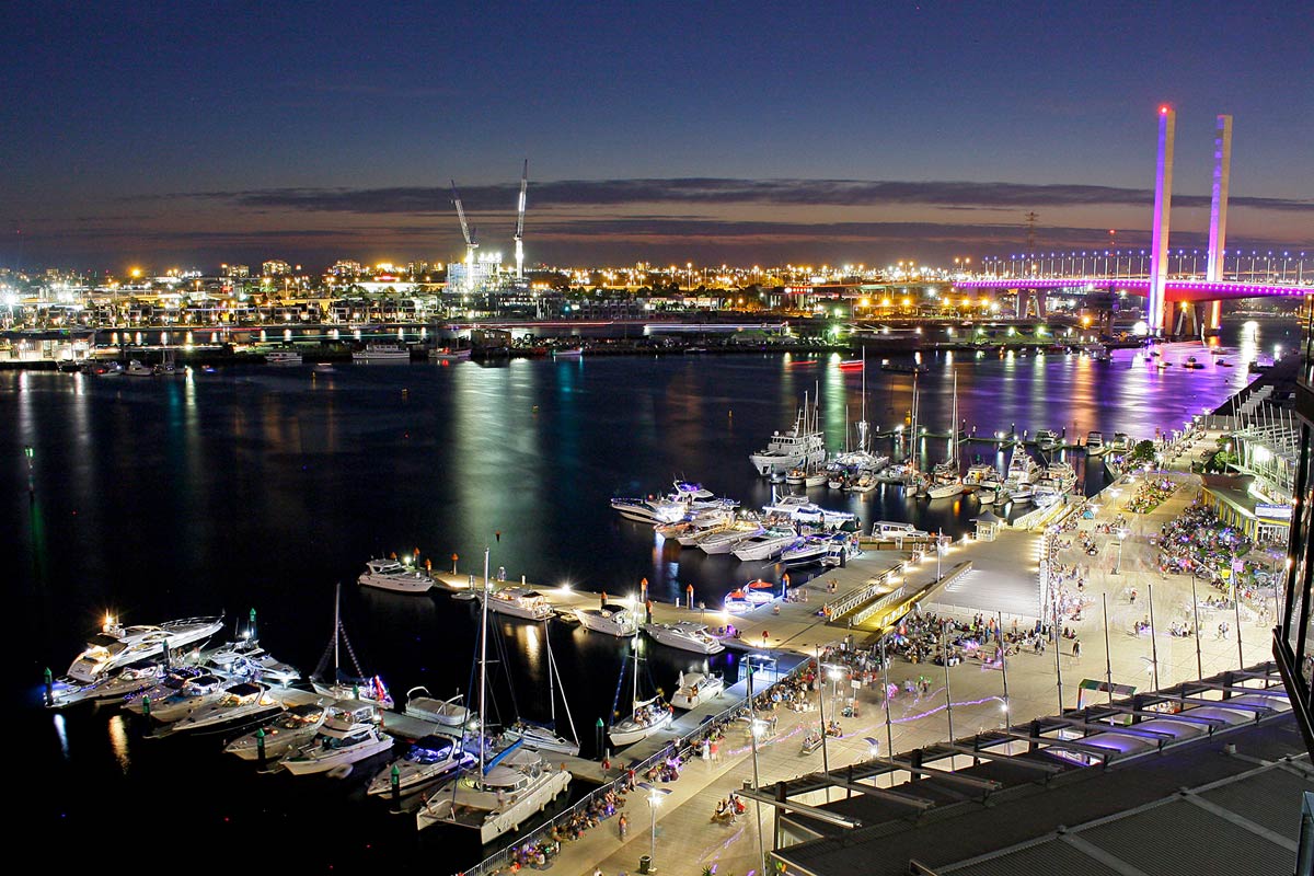 Aerial view of Melbourne City Marina showing the brightly lit waterfront, moored boats and the Bolte Bridge in the background