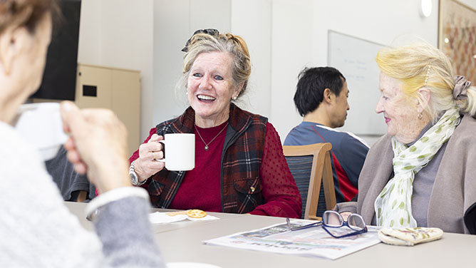Smiling older people at tables with cups and mugs