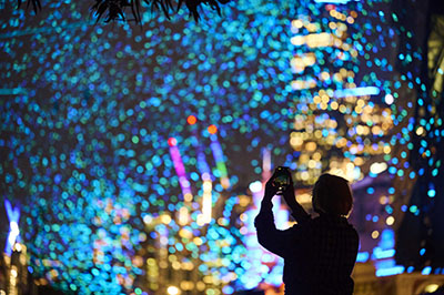 Photograph of someone taking a photograph at night of shimmering artwork