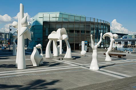 White fibreglass sculptures resembling figures and trees on paved area
