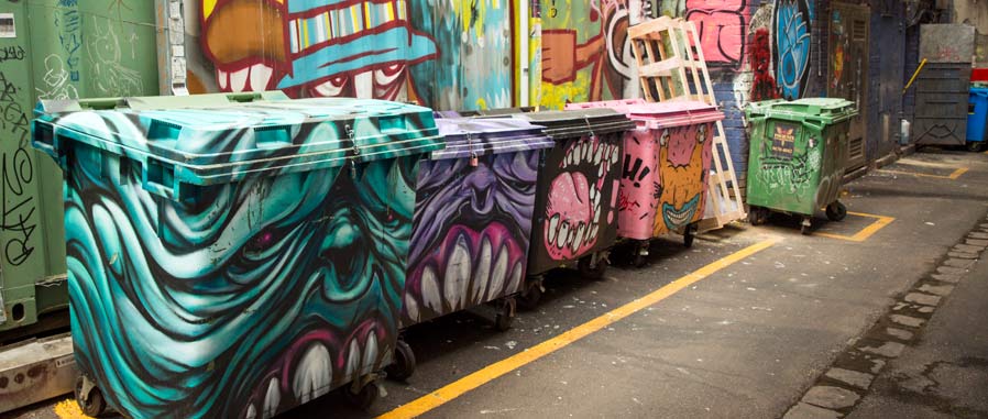 Bins decorated with street art in a laneway