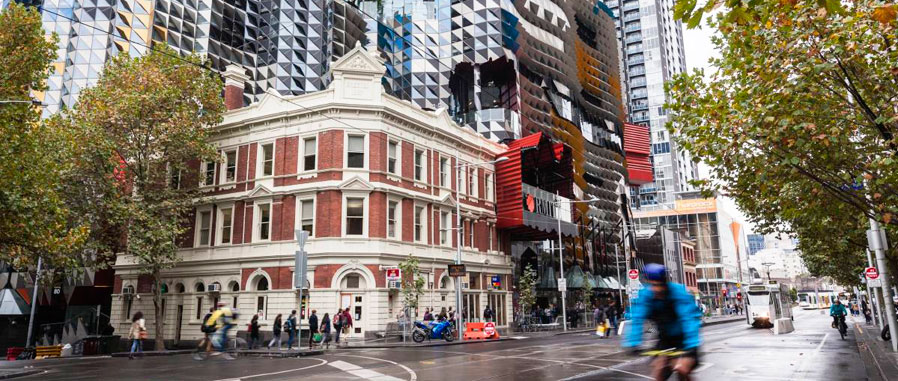 Melbourne city streetscape with RMIT building, cyclists and pedestrians