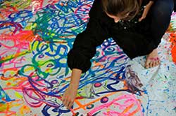 Person working on a large abstract painting in bright colours