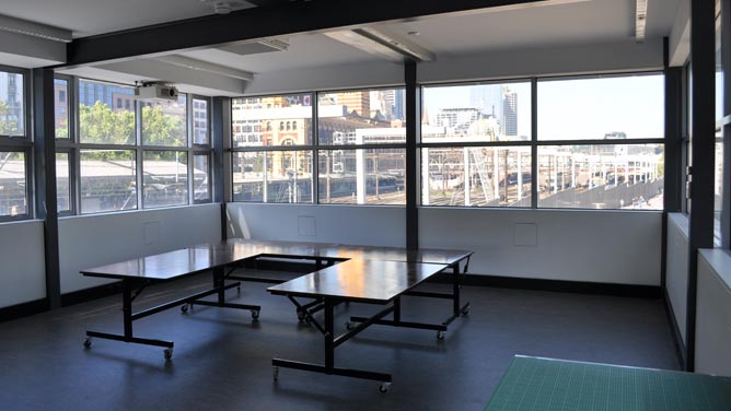 Signal studio on upper floor with small tables set in U-layout and windows on three sides with a view of Flinders Street station