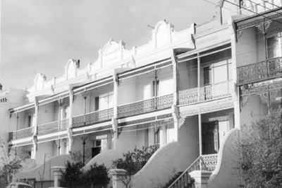 A black-and-white photography of traditional terrace houses with iron lattice on the balconies.