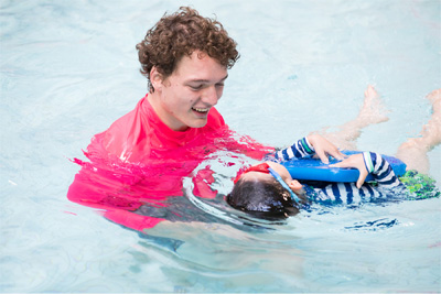 A swimming instructor assisting a child in a pool.