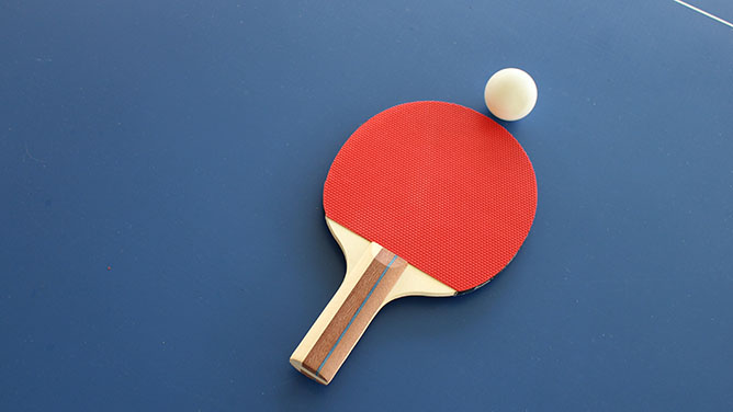 Table tennis bat and ball on blue background of table tennis table