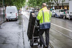 A delivery worker pushing a trolley stacked with crates