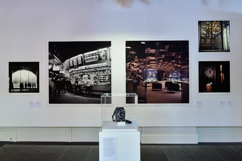 Gallery wall featuring five photographs and a glass display cabinet
