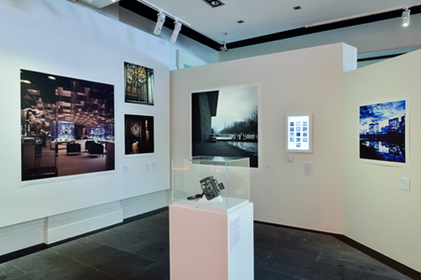 Corner of the gallery featuring five photographs and a glass display cabinet
