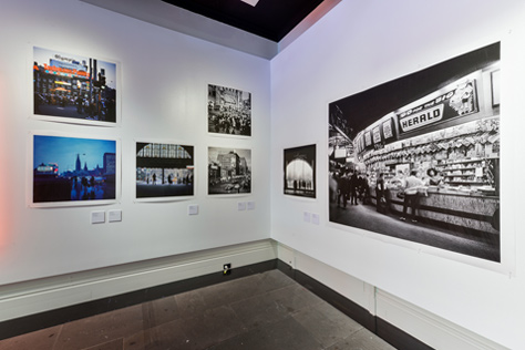 Five photographs on the corner of a white gallery walls
