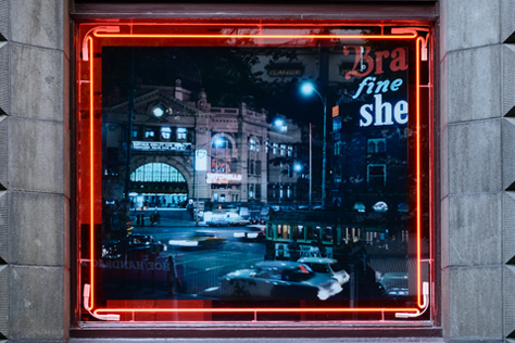 Photograph of Flinders Street station at night, encased in a red neon light frame