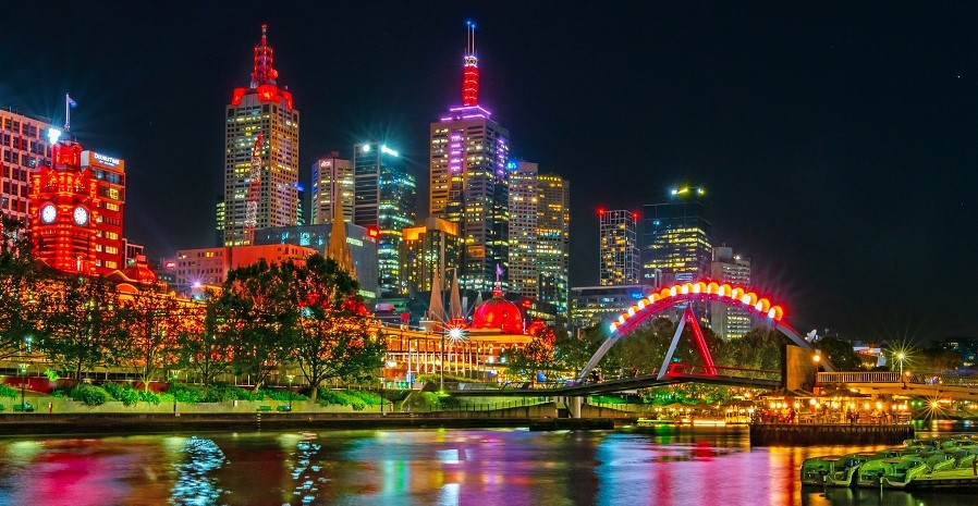 The city and river at night, with bright and colourful lights.