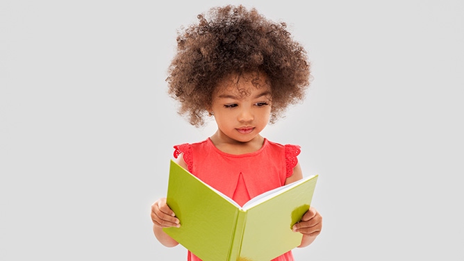 child with very curly hair reading a book