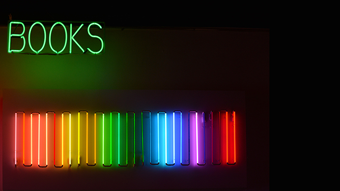 Neon sign with the word 'Books' and rainbow spectrum of book spines below